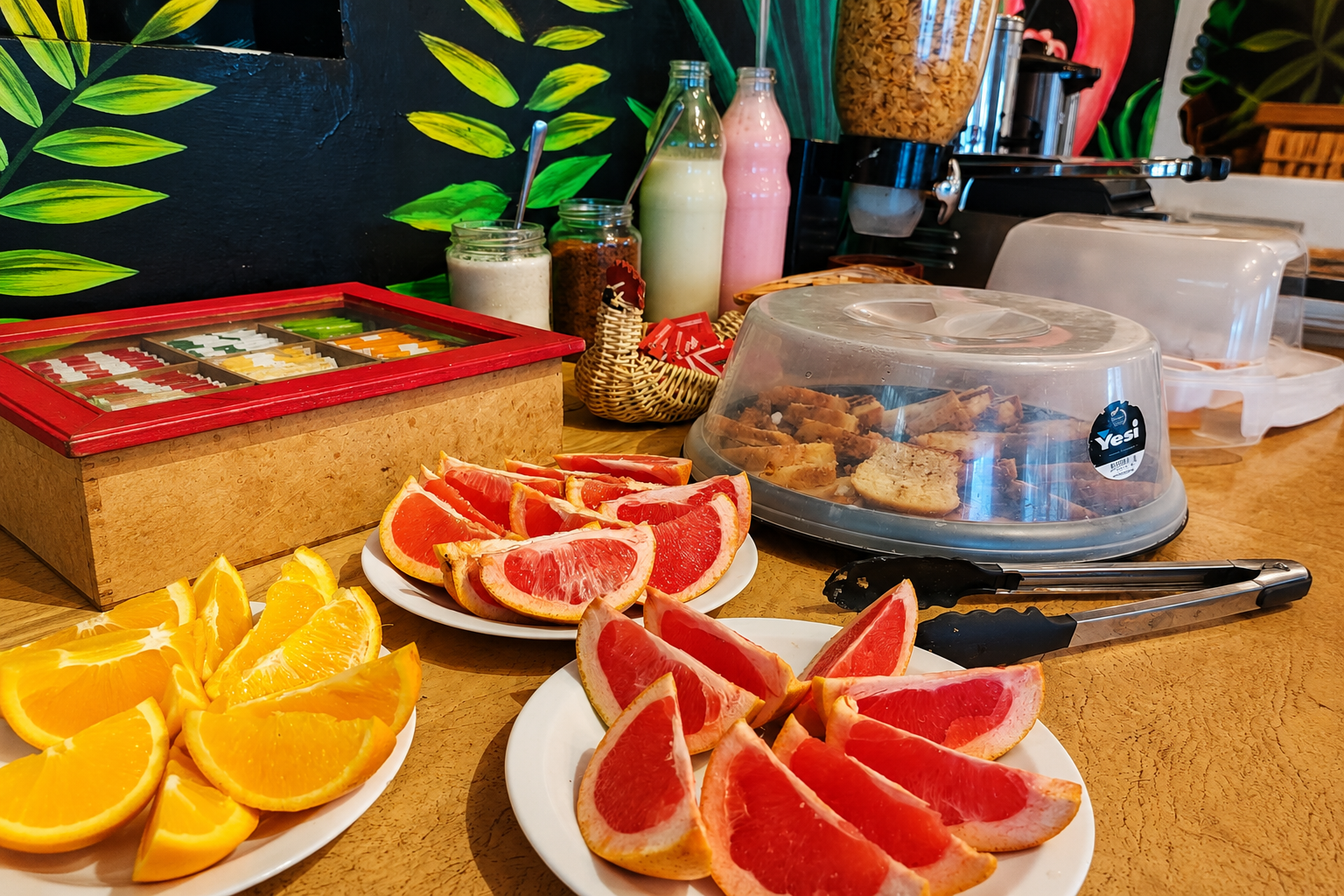 Mesa de desayuno con frutas cortadas, panificados y bebidas